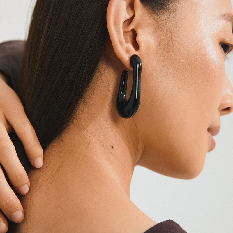 PILGRIM | ELIJAH RECYCLED BLACK EARRINGS - GOLD PLATED
Go with all your heart! The large, oval ELIJAH hoops from Pilgrim, crafted in black recycled acrylic, add an edgy retro touch to your favourite autumn-winter styles. Perfect for those looking for a street-ready accessory and who cherish a classic urban look! Style the earrings with a chunky jumper and an oversized blazer for a laid-back elegance that transitions effortlessly from day-to-night. 