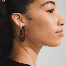 PILGRIM | ELIJAH RECYCLED BROWN EARRINGS - SILVER PLATED

Go with all your heart! The large, oval ELIJAH hoops from Pilgrim, in brown recycled acrylic, introduce an edgy retro vibe to your favourite AW styles. Perfect for those looking for a street-ready accessory and who cherish a classic urban look! Style the earrings with a chunky jumper and an oversized blazer for a laid-back elegance that transitions effortlessly from day-to-night