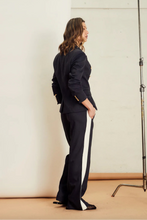 Load image into Gallery viewer, Introducing the new&nbsp; We are the others, Alba Pant in a rich indigo color, featuring a stylish contrast bone stripe down the side leg. Crafted from a comfy twill fabrication, these pants offer a relaxed fit and an elastic waist for ultimate comfort. Perfect for elevating your casual look or dressing up for a night out, the Alba Pant combines effortless style with everyday ease.
