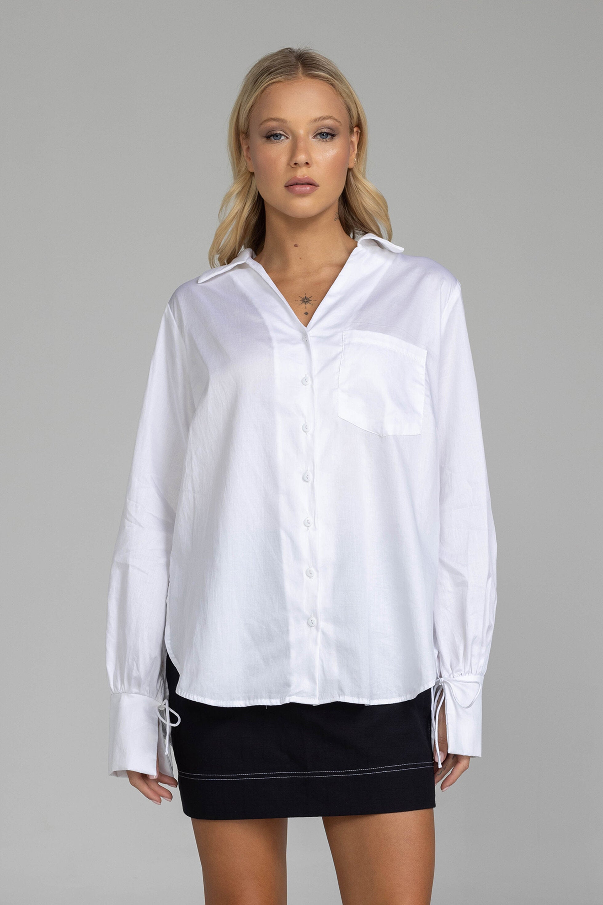 The distinguished Blak Atlas Shirt in crisp white combines every thing you need in a refined silhouette. Features include a v-neckline with collar, button-through front, and long sleeves culminating in deep cuffs with elegant tie closures. A discreet patch pocket adds functionality, while the back yoke with inverted box pleat ensures graceful movement. Sophisticated side-splits and a curved hemline complete this versatile piece, suitable for both professional and casual occasions.
Fabric composition -Cotton