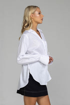 The distinguished Blak Atlas Shirt in crisp white combines every thing you need in a refined silhouette. Features include a v-neckline with collar, button-through front, and long sleeves culminating in deep cuffs with elegant tie closures. A discreet patch pocket adds functionality, while the back yoke with inverted box pleat ensures graceful movement. Sophisticated side-splits and a curved hemline complete this versatile piece, suitable for both professional and casual occasions.
Fabric composition -Cotton