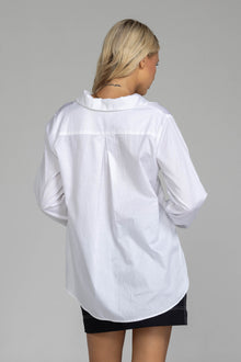 The distinguished Blak Atlas Shirt in crisp white combines every thing you need in a refined silhouette. Features include a v-neckline with collar, button-through front, and long sleeves culminating in deep cuffs with elegant tie closures. A discreet patch pocket adds functionality, while the back yoke with inverted box pleat ensures graceful movement. Sophisticated side-splits and a curved hemline complete this versatile piece, suitable for both professional and casual occasions.
Fabric composition -Cotton