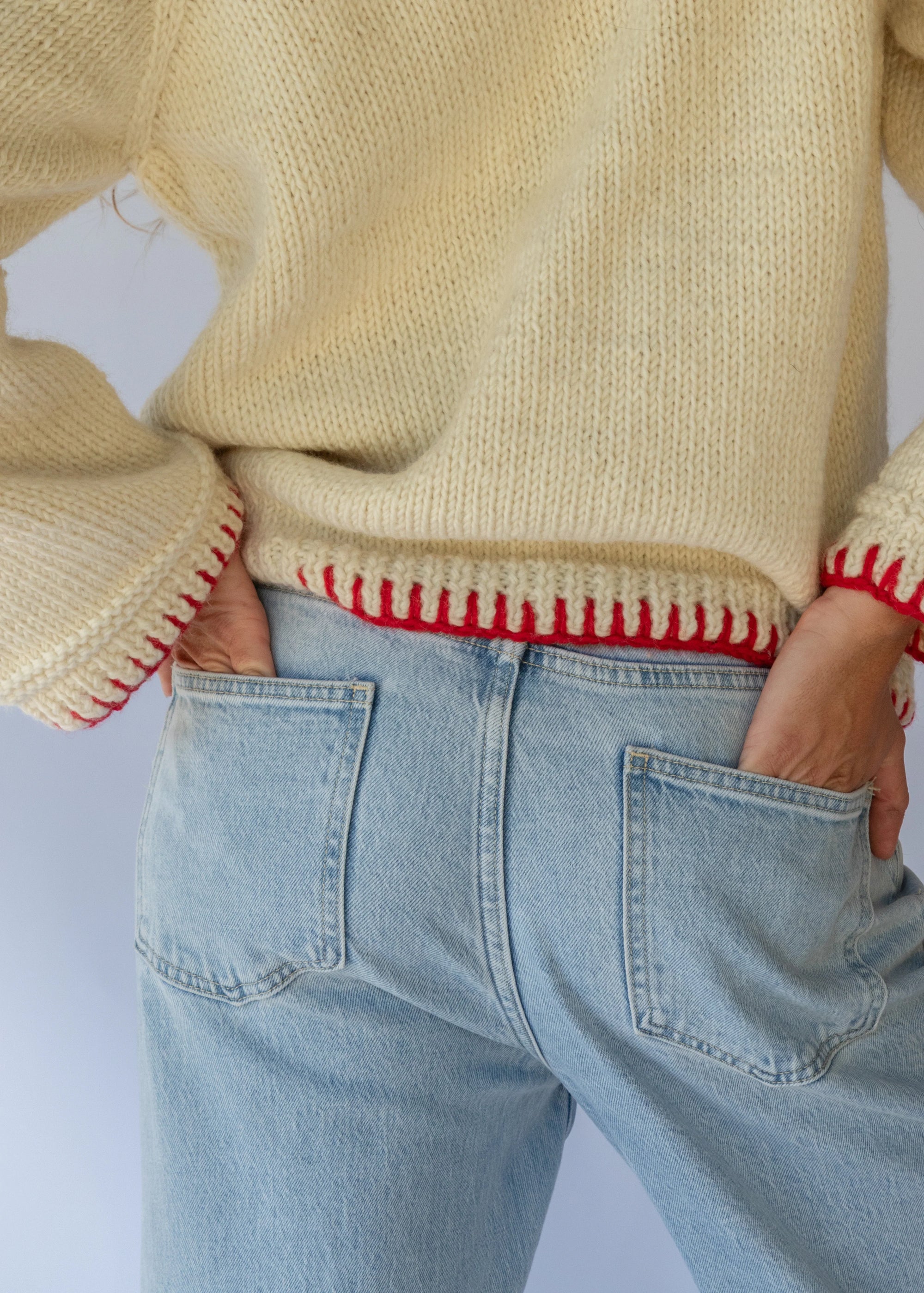 HOBO AND HATCH | Sol Sweater - Chilli - Hand-knitted cream wool sweater crafted from 100% New Zealand wool, featuring playful embroidered chilli motifs and contrasting red blanket-stitch detailing along the hem, neckline, and sleeves. Designed with a relaxed fit, round neckline, and open sleeves for effortless layering or standalone wear. Ethically handcrafted in Nepal alongside local artisans.