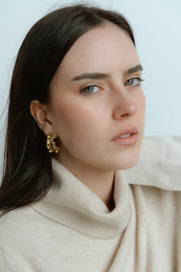 Textured, bold, and effortlessly chic—the Castel &amp; Co Crinkle Earrings in Gold bring a sculptural edge to classic jewellery. Their organic, rippled design reflects light beautifully, creating a statement that feels both modern and timeless. Perfect for adding depth to minimal looks or enhancing an already bold ensemble, these earrings offer a sophisticated yet playful finish to any outfit.

Main material: gold plating, stainless steel
Closure type: stud
Earrings size: 3 x 1,5 cm
Waterproof and hypoaller