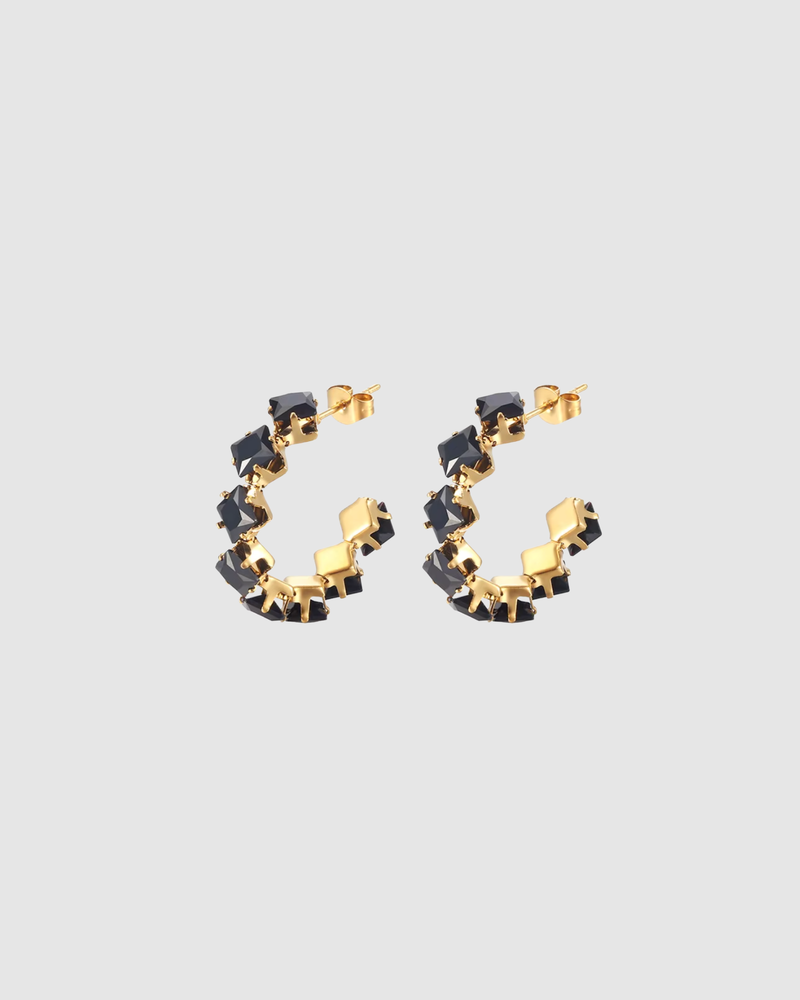 Freya Earrings by Castel & Co are gold-plated stainless steel hoop earrings featuring sparkling cubic zirconia accents for a refined, radiant finish. Designed in a modern circular silhouette that catches the light from every angle, balancing elegance with contemporary style. Measuring 3 x 3 cm with a secure stud closure. Lightweight (5g), waterproof, and hypoallergenic.