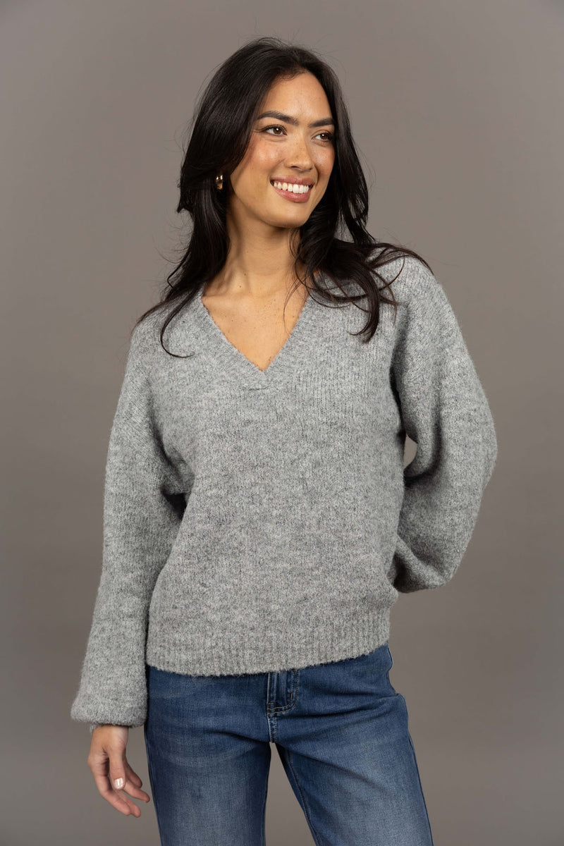 Humidity Lifestyle Nouveau V Neck Jumper in a soft wool blend, featuring a relaxed, oversized fit with a low V-neckline and subtle bell sleeves. Designed with ribbed cuffs and hem that sit just below the hips, this plush, lightweight jumper has a gentle, fluffy texture ideal for layering over denim or dresses.