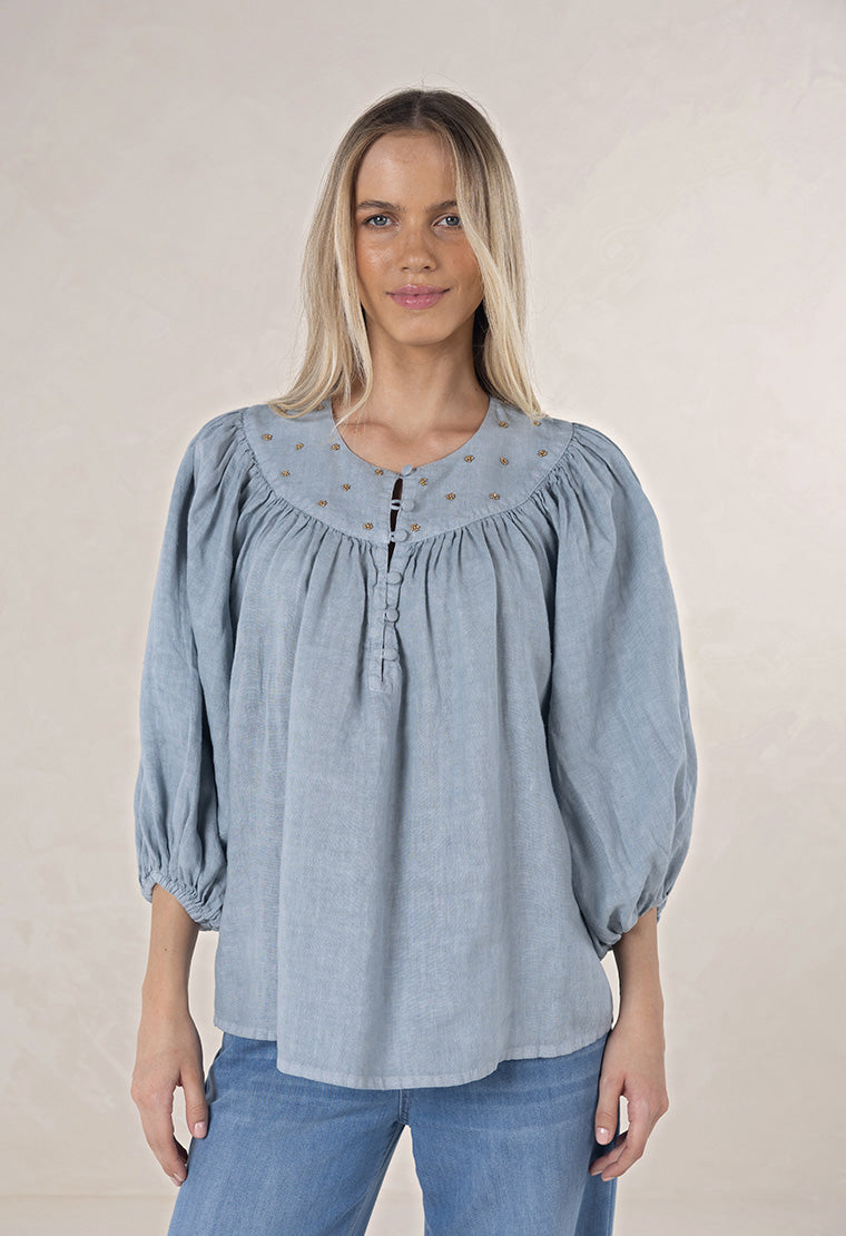 HUMIDITY LIFESTYLE - BAROQUE BLOUSE
A timeless piece with a touch of artisanal charm. This beautifully oversized blouse is crafted from 100% linen- breathable and natural. Designed with softly billowing sleeves and handcrafted bead detailing, it’s all about effortless elegance. This piece pairs just as beautifully with tailored pants as it does with your favourite denims.
