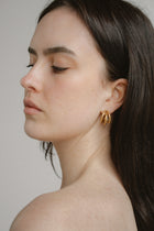 Hadley Hoops by Castel & Co are stainless steel textured hoop earrings available in gold-plated and silver-tone finishes. Designed with a bold yet timeless sculptural silhouette and a light-catching textured finish, they add impact while remaining versatile for everyday wear. Measuring 3 x 1.6 cm with a secure stud closure. Lightweight (9g), waterproof, and hypoallergenic.