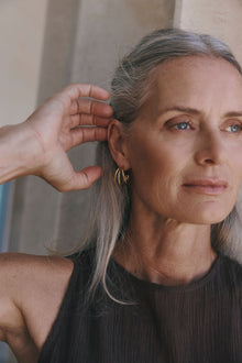 Isla Hoops by Castel & Co are gold-plated stainless steel hoop earrings featuring interlocking bands that create depth and movement with every turn. Their layered silhouette adds a sculptural edge to the classic hoop, striking a balance between statement and sophistication. Designed to stand out while remaining versatile for everyday wear. Measuring 2.5 x 1.6 cm with a secure stud closure. Lightweight (8g), waterproof, and hypoallergenic.