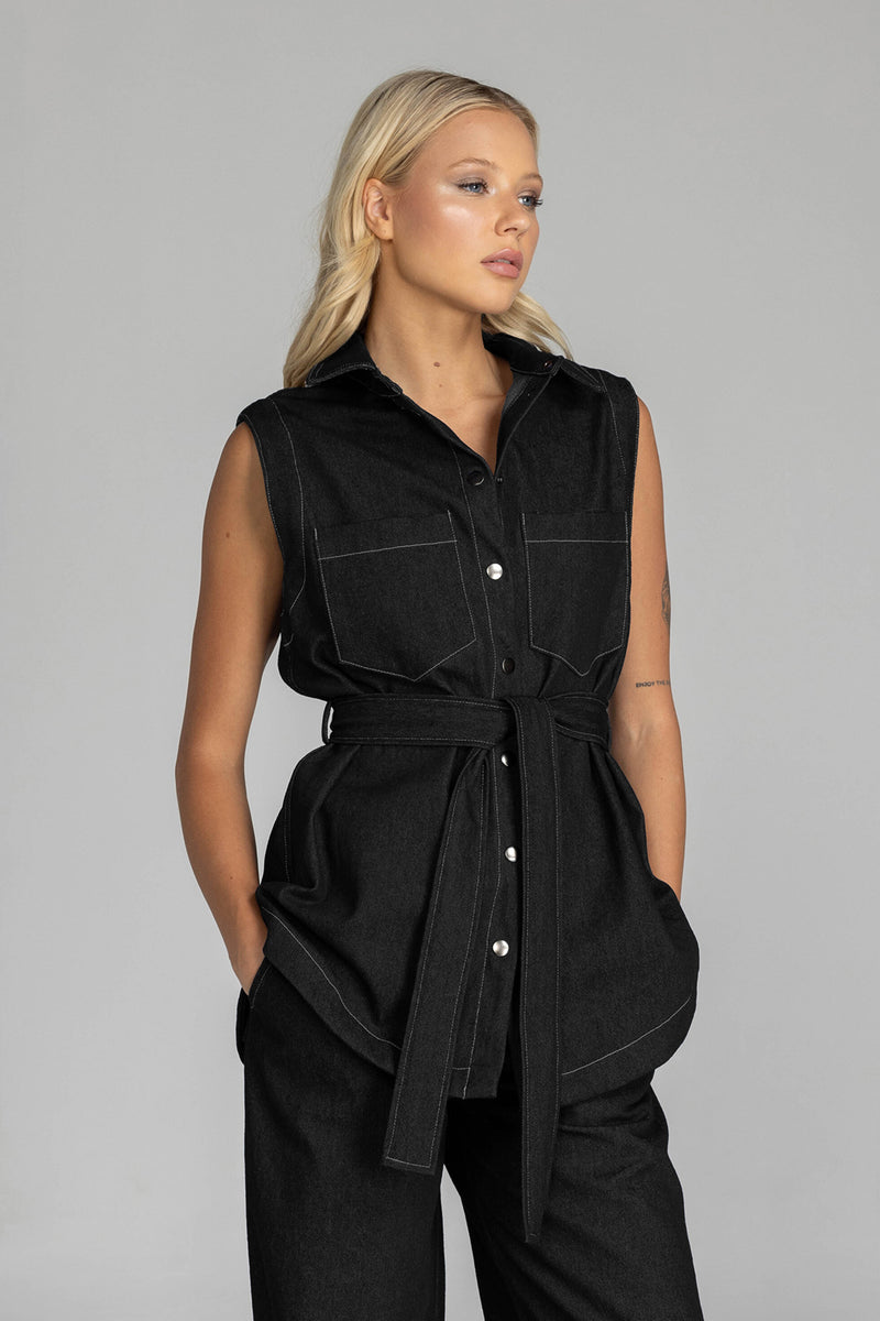 The BLAK Kent Vest offers quality cotton denim with traditional white topstitching in a comfortable relaxed fit. Features include easy-to-use dome closures, a flattering collar, and practical front pockets for your essentials. The included tie belt helps create your ideal silhouette, while the thoughtfully designed back with inverted pleat ensures both comfort and movement. 