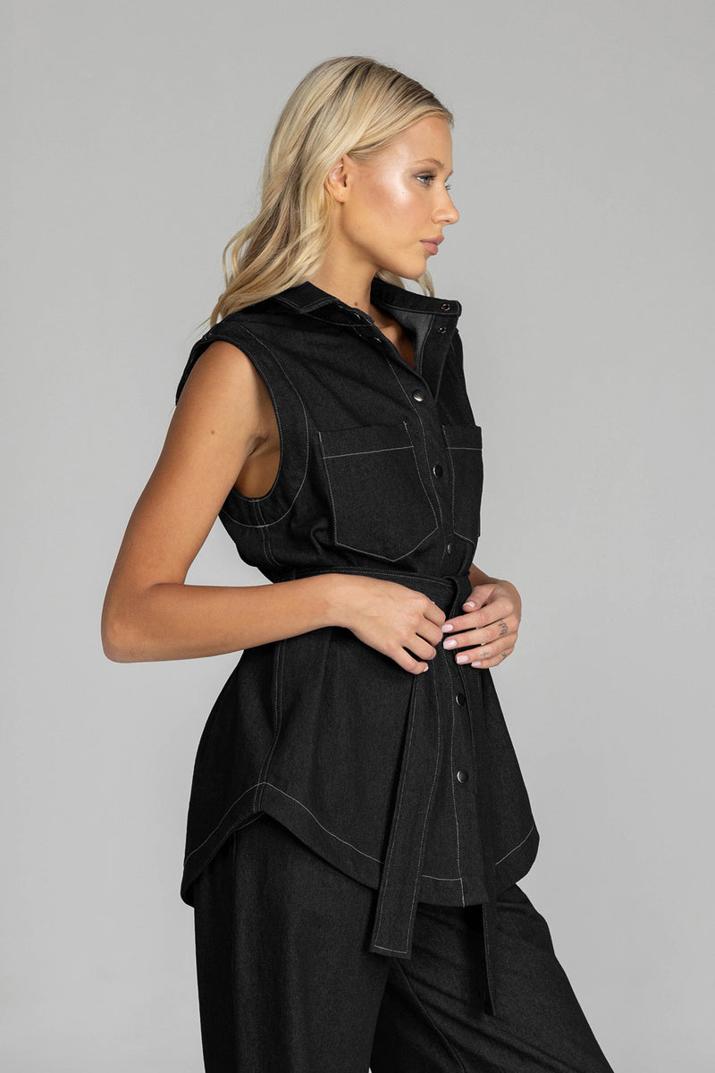 The BLAK Kent Vest offers quality cotton denim with traditional white topstitching in a comfortable relaxed fit. Features include easy-to-use dome closures, a flattering collar, and practical front pockets for your essentials. The included tie belt helps create your ideal silhouette, while the thoughtfully designed back with inverted pleat ensures both comfort and movement. 