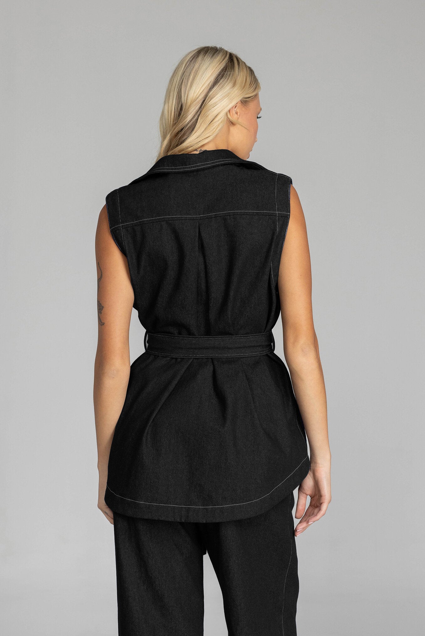 The BLAK Kent Vest offers quality cotton denim with traditional white topstitching in a comfortable relaxed fit. Features include easy-to-use dome closures, a flattering collar, and practical front pockets for your essentials. The included tie belt helps create your ideal silhouette, while the thoughtfully designed back with inverted pleat ensures both comfort and movement. 