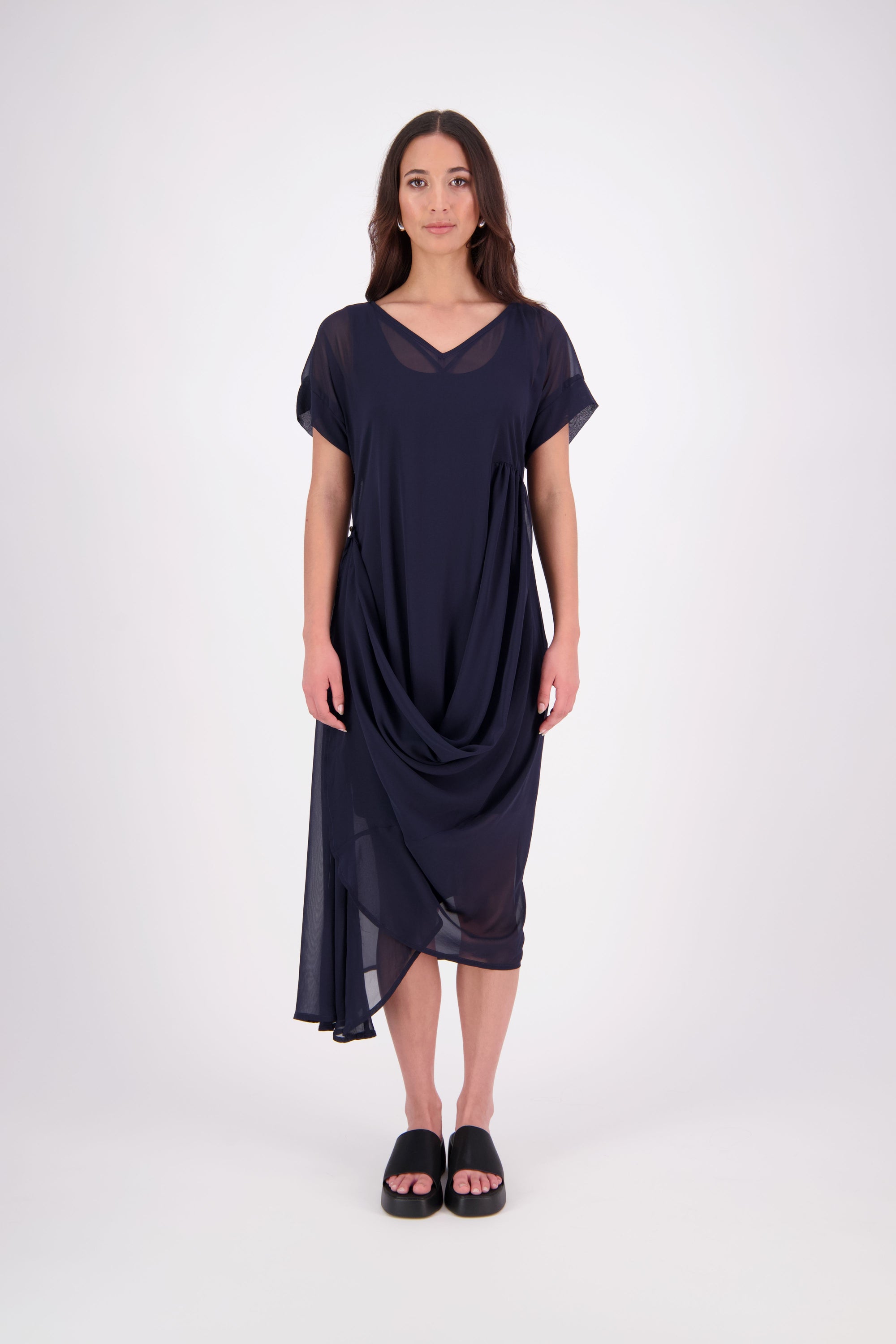The NES Kira Dress blends the best of two favourites – the elegance of the Dreamliner and the versatility of the Flow Dress. With a relaxed drape and subtle tailoring, it features a flattering V-neckline, rouching under the bust on one side, cap sleeves, and adjustable button loop detailing for styling versatility (one dress - wear it 3 ways).