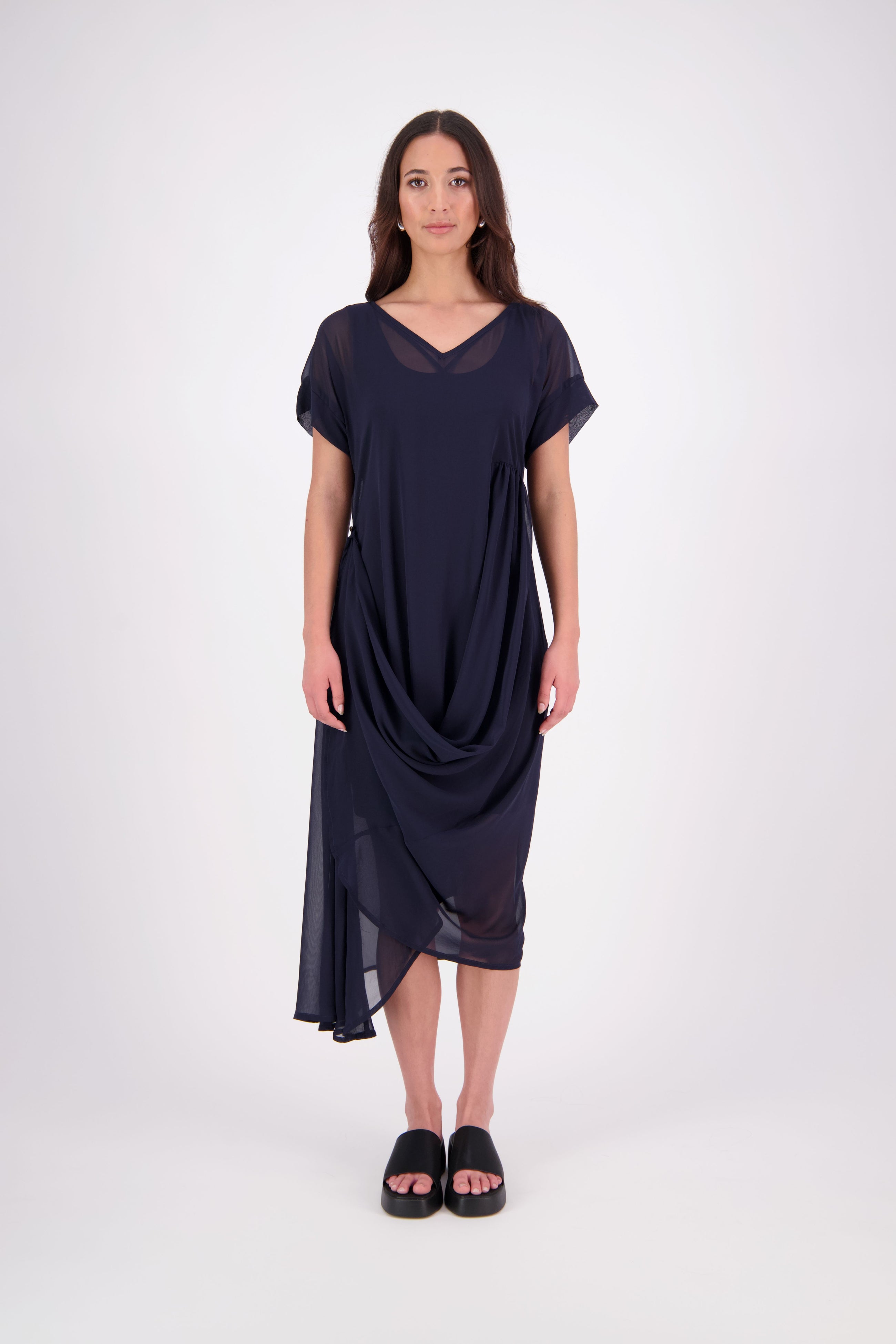 The NES Kira Dress blends the best of two favourites – the elegance of the Dreamliner and the versatility of the Flow Dress. With a relaxed drape and subtle tailoring, it features a flattering V-neckline, rouching under the bust on one side, cap sleeves, and adjustable button loop detailing for styling versatility (one dress - wear it 3 ways).