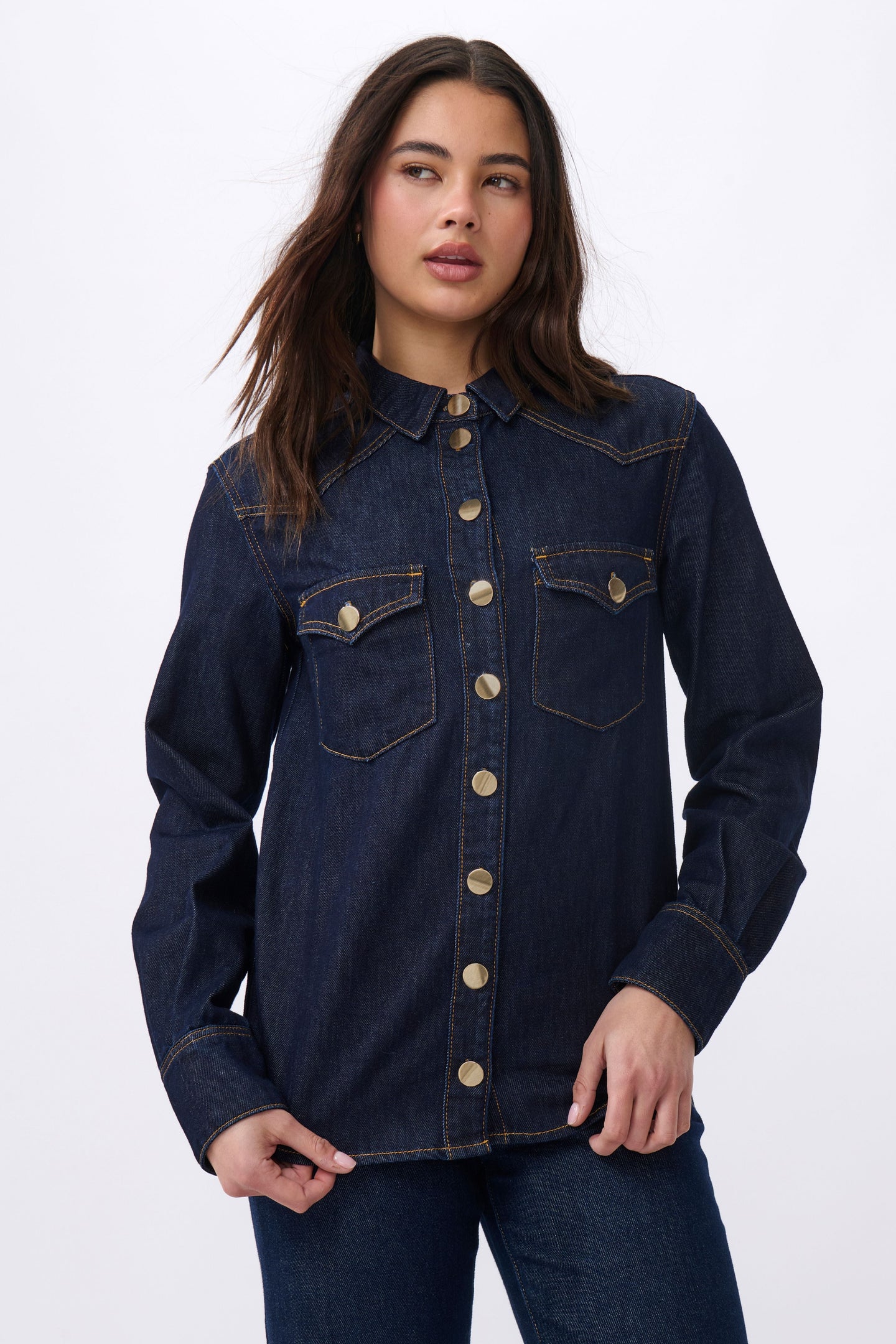 Kireina London Shirt is destined to be a lifelong keepsake and closet staple. This western-inspired denim shirt is perfectly washed in Indigo denim. It has a boyish structured fit, two single-point pockets, single point yokes, and striking gold shank button. Wear this with your favourite jeans for a head-to-toe denim look or unbuttoned over an easy dress.

FEATURES:
- Button-through front
- Single point yokes
- Single point buttoned pockets
- 2-button barrel cuffs