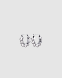 Margot Earrings by Castel & Co feature a softly sculpted gold-plated stainless steel hoop finished with a luminous imitation pearl drop. Designed to feel both modern and timeless, they bring a refined edge to everyday styling while also suiting occasion wear. Measuring 2.4 x 2.6 cm with a secure hinge closure. Lightweight (10g), waterproof, and hypoallergenic.