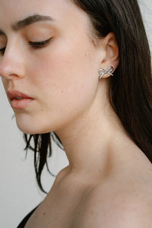 Refined yet playful, the Castel & Co Mini Bow Earrings in medium silver give the classic bow a modern edge. Their polished finish and graceful curves create subtle shine, offering a versatile stud that feels both feminine and contemporary.

Material: Stainless steel
Closure Type: Stud
Earring Size: 20 mm
Waterproof and hypoallergenic
Weight: 1.5g