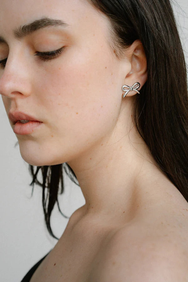Refined yet playful, the Castel & Co Mini Bow Earrings in medium silver give the classic bow a modern edge. Their polished finish and graceful curves create subtle shine, offering a versatile stud that feels both feminine and contemporary.

Material: Stainless steel
Closure Type: Stud
Earring Size: 20 mm
Waterproof and hypoallergenic
Weight: 1.5g
