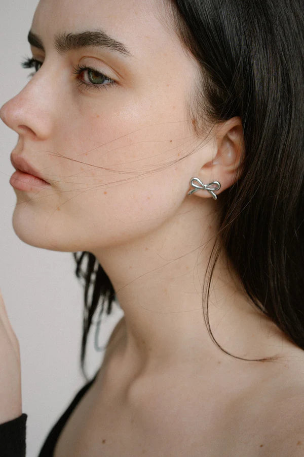 Refined yet playful, the Castel & Co Mini Bow Earrings in medium silver give the classic bow a modern edge. Their polished finish and graceful curves create subtle shine, offering a versatile stud that feels both feminine and contemporary.

Material: Stainless steel
Closure Type: Stud
Earring Size: 20 mm
Waterproof and hypoallergenic
Weight: 1.5g