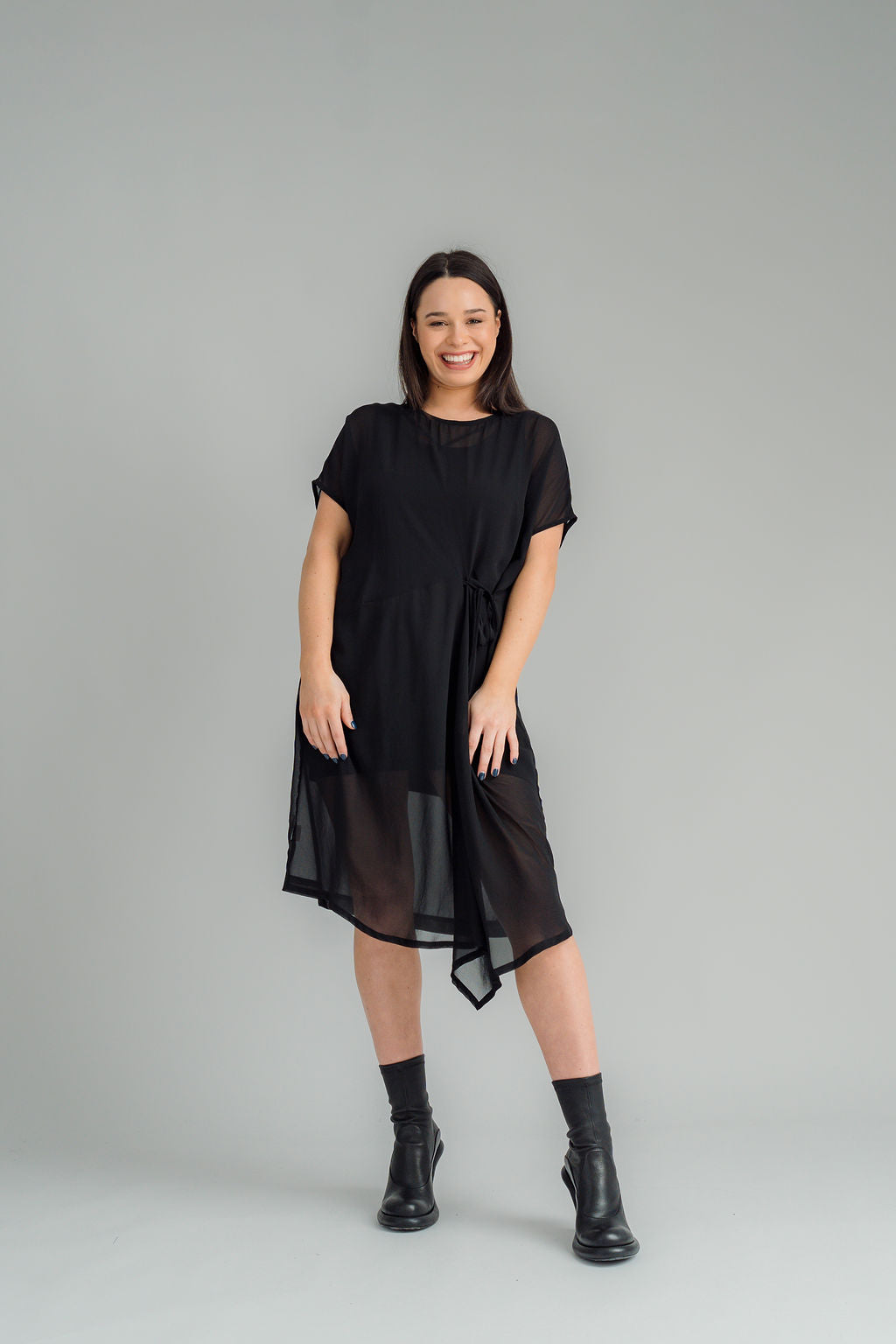 Our NES Aria Dress is a NES favourite and a must-have wardrobe piece! Featuring subtle batwing sleeves, a scoop neck, and front dart and tie detailing, this dress offers a flattering and versatile fit. The front tie can be styled tight or loose for added customization. This mid-length dress is perfect for any occasion, whether dressed up or down. We love styling the chiffon Aria Dress with our NES Lattice Slip underneath for added layering. Wear it as a standalone dress or layer it as a tunic over pants for
