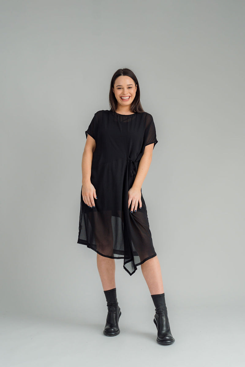 Our NES Aria Dress is a NES favourite and a must-have wardrobe piece! Featuring subtle batwing sleeves, a scoop neck, and front dart and tie detailing, this dress offers a flattering and versatile fit. The front tie can be styled tight or loose for added customization. This mid-length dress is perfect for any occasion, whether dressed up or down. We love styling the chiffon Aria Dress with our NES Lattice Slip underneath for added layering. Wear it as a standalone dress or layer it as a tunic over pants for