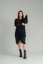The NES Glide Dress is inspired by our best-selling NES Flow Dress, now with long sleeves for added warmth and versatility. This multi-seasonal dress is perfect for both casual and formal occasions, offering endless styling options. Wear it draped down the front for a relaxed look, or cinch it up at the side with the adjustable side button and hem loopers for a more defined shape. The long sleeves feature elasticated loopers and a metal shank cuff button for added detail. Style it with our Lattice Slip, sne
