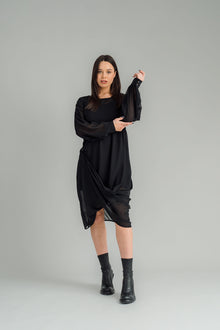 The NES Glide Dress is inspired by our best-selling NES Flow Dress, now with long sleeves for added warmth and versatility. This multi-seasonal dress is perfect for both casual and formal occasions, offering endless styling options. Wear it draped down the front for a relaxed look, or cinch it up at the side with the adjustable side button and hem loopers for a more defined shape. The long sleeves feature elasticated loopers and a metal shank cuff button for added detail. Style it with our Lattice Slip, sne