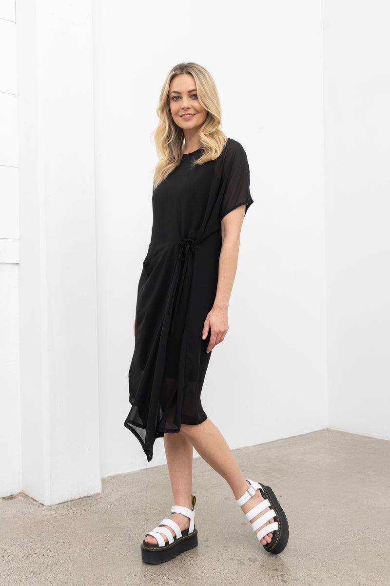 Our NES Aria Dress is a NES favourite and a must-have wardrobe piece! Featuring subtle batwing sleeves, a scoop neck, and front dart and tie detailing, this dress offers a flattering and versatile fit. The front tie can be styled tight or loose for added customization. This mid-length dress is perfect for any occasion, whether dressed up or down. We love styling the chiffon Aria Dress with our NES Lattice Slip underneath for added layering. Wear it as a standalone dress or layer it as a tunic over pants for