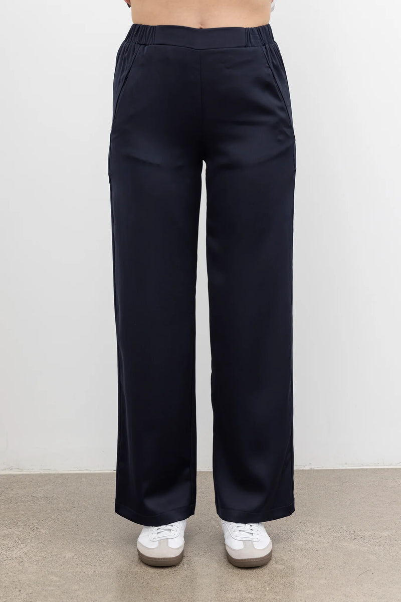 The NES Satin Gin Pants are our absolute top-selling dressy essential pants, designed to flatter all body shapes. Featuring a classic cut, these versatile pants are perfect for both dressing up and down, making them an ideal choice for an evening out or as a chic, dressed-up everyday look. The flat front, covered elasticated back, and flattering angled pockets provide both comfort and sophistication. Crafted from a floaty, cool-to-the-touch poly satin fabric that’s anti-crease