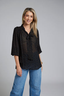 N-E-S Esme Top, designed and made in NZ – a relaxed women’s top with curved front and back hem, finishing just below the waistband; lightweight and breathable, available in Black Polka Dot (100% viscose georgette with butter-yellow mini spots) or Ivory Spot (100% polyester satin-back crepe with bronze oversized spots) for soft drape, gentle movement, and effortless, polished everyday wear.