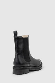 Chaos & Harmony OLLIE Boot, a blend of sustainable fashion and distinctive design. Crafted from black recycled leather, these boots are a testament to both style and environmental consciousness. The square toe shape sets a contemporary tone, offering a unique silhouette that stands out. Black recycled leather chelsea boot, Soft leather lined