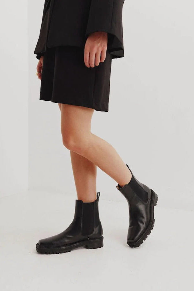 Chaos & Harmony OLLIE Boot, a blend of sustainable fashion and distinctive design. Crafted from black recycled leather, these boots are a testament to both style and environmental consciousness. The square toe shape sets a contemporary tone, offering a unique silhouette that stands out. Black recycled leather chelsea boot, Soft leather lined