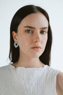 Modern and sculptural, the Castel & Co Remi Earrings in polished silver feature an open, organic form with a textured finish. Their irregular shape adds depth and edge, while the cool silver tone brings a sleek, contemporary feel. A striking statement stud that balances artistry with everyday versatility.

Material: Stainless steel
Closure Type: Stud
Earring Size: 3 x 2.4 cm
Waterproof and hypoallergenic
Weight: 8g