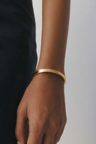 RYLEE Bracelet by Castel & Co in gold with a slim, refined silhouette designed for effortless everyday wear. Clean and modern in feel, it sits neatly on the wrist, perfect for stacking or wearing on its own. Crafted from stainless steel with gold plating, featuring a 5.8 cm diameter and 0.4 cm width. Waterproof, hypoallergenic, and lightweight at 15g.