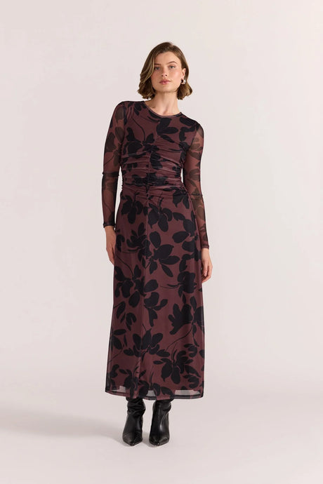 the Staple the Label Olina Mesh Maxi Dress makes a statement through silhouette and texture. Crafted in a soft stretch mesh with an all-over black floral print on a rich mulberry base, this dress features flattering ruched detailing through the bodice, sheer long sleeves, and a softly flared hemline that skims the body. The sheer mesh overlay is balanced with full lining through the body for comfort and coverage, making it the ideal piece for elevated eventwear or occasion styling.