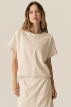 Featuring a soft faux leather in a fresh Ecru shade, the POL Belmond Top has a boxy, t-shirt inspired silhouette.

-Round neckline.
-Covered button fastening at the back neck.
-Dropped armholes.
-Short sleeves finish in a cuff with covered button fastening.