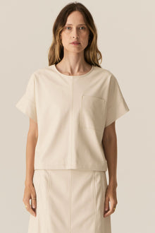Featuring a soft faux leather in a fresh Ecru shade, the POL Belmond Top has a boxy, t-shirt inspired silhouette.

-Round neckline.
-Covered button fastening at the back neck.
-Dropped armholes.
-Short sleeves finish in a cuff with covered button fastening.