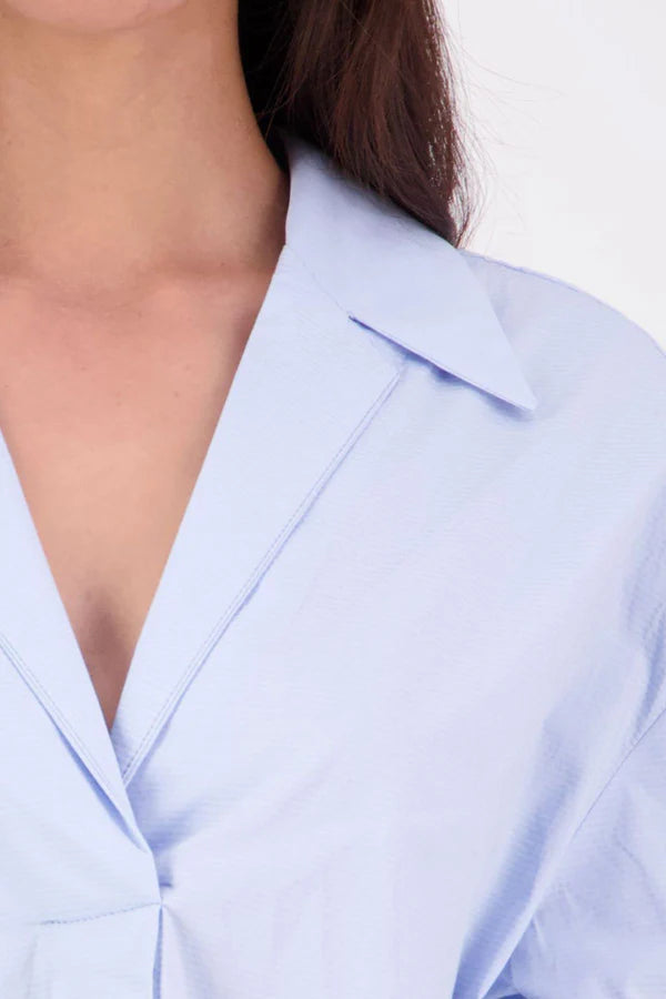 The N-E-S Fara Shirt blends classic tailoring with soft, modern touches. Featuring 7/8 sleeves with three layers of shirring at the cuffs, a traditional collar flowing into an open V-neck and centre front pleat. The drop-back design reveals a cross-over keyhole and centre back button detail. Style the sleeves your way—worn down, ruched up, or tucked under—for versatile, effortless dressing.
Composition: Sky (fine seersucker) - cotton, spandex | Oyster grey stripe cotton, polyamide, elastine.