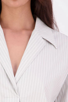 The N-E-S Fara Shirt blends classic tailoring with soft, modern touches. Featuring 7/8 sleeves with three layers of shirring at the cuffs, a traditional collar flowing into an open V-neck and centre front pleat. The drop-back design reveals a cross-over keyhole and centre back button detail. Style the sleeves your way—worn down, ruched up, or tucked under—for versatile, effortless dressing.
Composition: Sky (fine seersucker) - cotton, spandex | Oyster grey stripe cotton, polyamide, elastine.