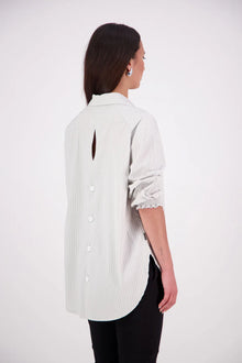 The N-E-S Fara Shirt blends classic tailoring with soft, modern touches. Featuring 7/8 sleeves with three layers of shirring at the cuffs, a traditional collar flowing into an open V-neck and centre front pleat. The drop-back design reveals a cross-over keyhole and centre back button detail. Style the sleeves your way—worn down, ruched up, or tucked under—for versatile, effortless dressing.
Composition: Sky (fine seersucker) - cotton, spandex | Oyster grey stripe cotton, polyamide, elastine.