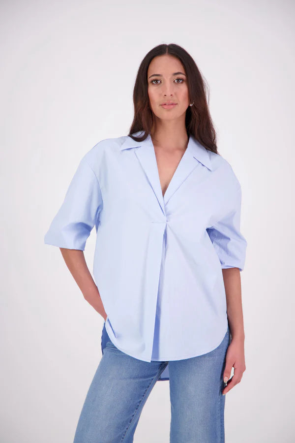 The N-E-S Fara Shirt blends classic tailoring with soft, modern touches. Featuring 7/8 sleeves with three layers of shirring at the cuffs, a traditional collar flowing into an open V-neck and centre front pleat. The drop-back design reveals a cross-over keyhole and centre back button detail. Style the sleeves your way—worn down, ruched up, or tucked under—for versatile, effortless dressing.
Composition: Sky (fine seersucker) - cotton, spandex | Oyster grey stripe cotton, polyamide, elastine.