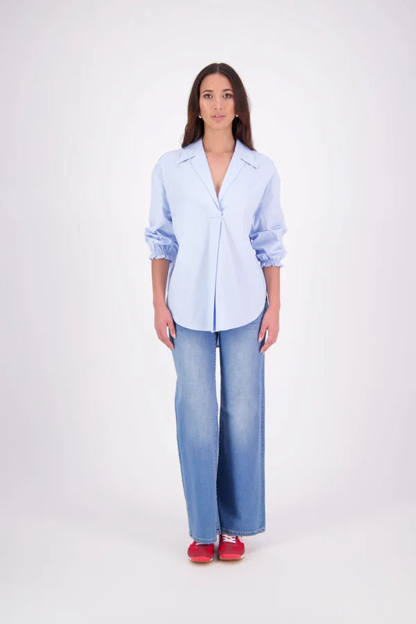 The N-E-S Fara Shirt blends classic tailoring with soft, modern touches. Featuring 7/8 sleeves with three layers of shirring at the cuffs, a traditional collar flowing into an open V-neck and centre front pleat. The drop-back design reveals a cross-over keyhole and centre back button detail. Style the sleeves your way—worn down, ruched up, or tucked under—for versatile, effortless dressing.
Composition: Sky (fine seersucker) - cotton, spandex | Oyster grey stripe cotton, polyamide, elastine.