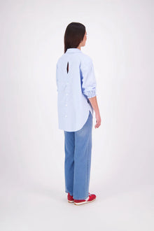The N-E-S Fara Shirt blends classic tailoring with soft, modern touches. Featuring 7/8 sleeves with three layers of shirring at the cuffs, a traditional collar flowing into an open V-neck and centre front pleat. The drop-back design reveals a cross-over keyhole and centre back button detail. Style the sleeves your way—worn down, ruched up, or tucked under—for versatile, effortless dressing.
Composition: Sky (fine seersucker) - cotton, spandex | Oyster grey stripe cotton, polyamide, elastine.