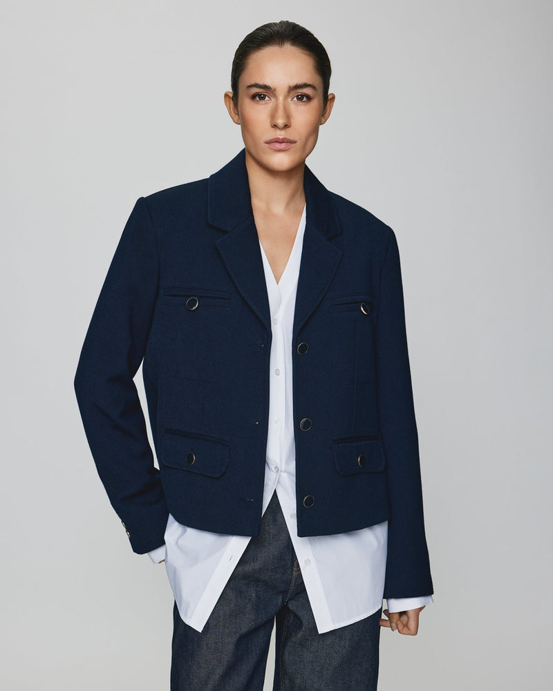 MSCH | ELINA BLAZER

A short, navy blue blazer with dark blue buttons with gold rim. These buttons is both down the front and on the cuffs. The blazer features a front pocket design inspired by a military jacket. Style it with a pair of jeans for a cool and causal look or with the matching skirt.

This blazer has a boxy fit. The model is 177cm and wears a size S.

Composition: 50% Recycled Polyester, 35% Viscose &amp; 15% Polyester