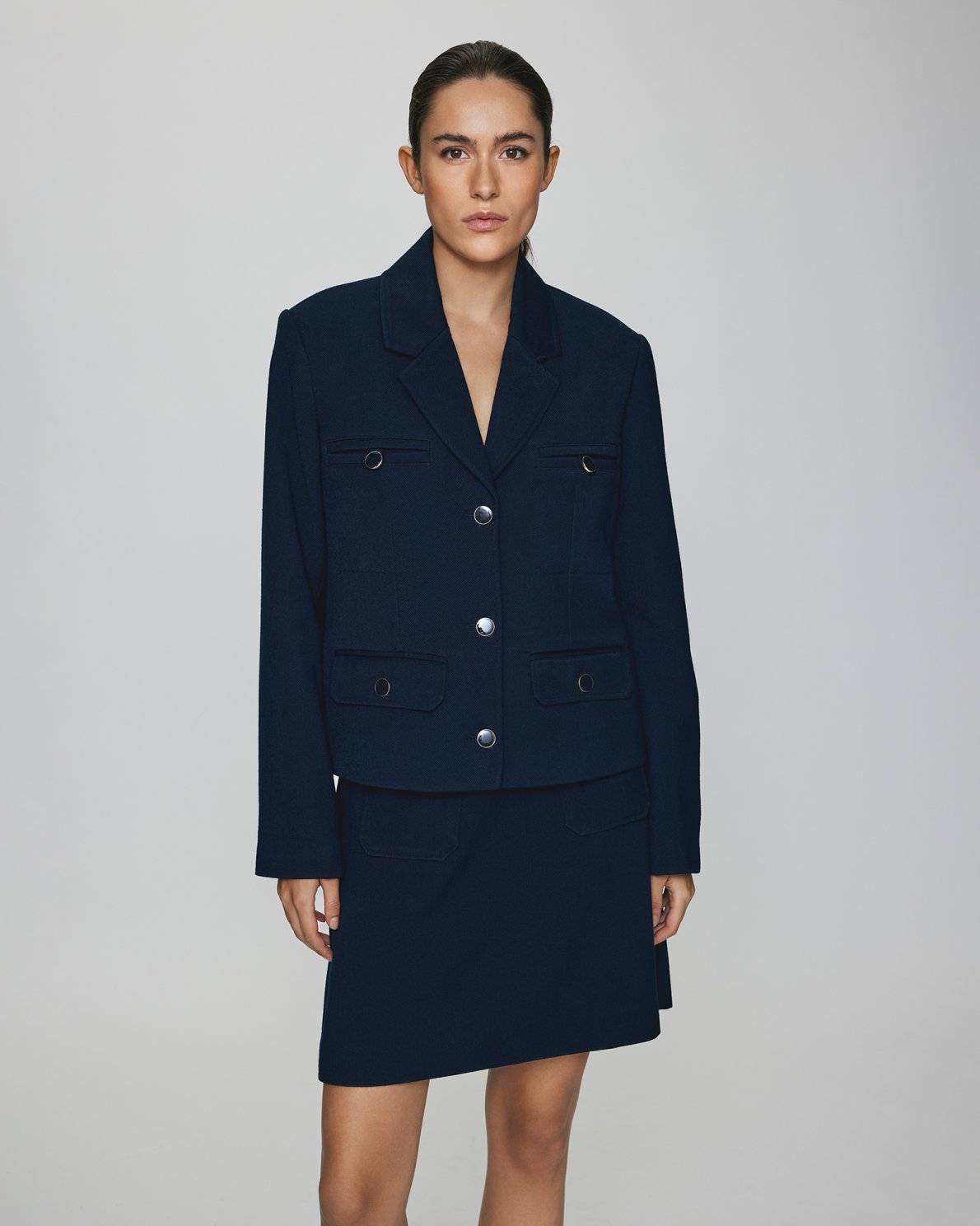 MSCH | ELINA BLAZER

A short, navy blue blazer with dark blue buttons with gold rim. These buttons is both down the front and on the cuffs. The blazer features a front pocket design inspired by a military jacket. Style it with a pair of jeans for a cool and causal look or with the matching skirt.

This blazer has a boxy fit. The model is 177cm and wears a size S.

Composition: 50% Recycled Polyester, 35% Viscose &amp; 15% Polyester