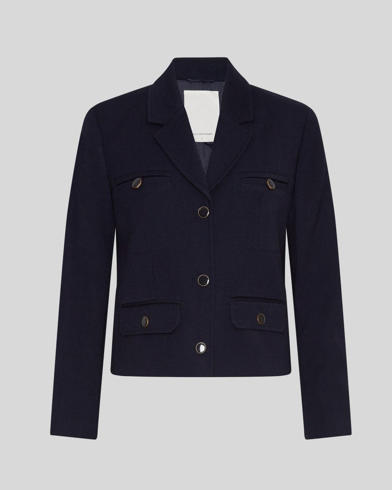 MSCH | ELINA BLAZER

A short, navy blue blazer with dark blue buttons with gold rim. These buttons is both down the front and on the cuffs. The blazer features a front pocket design inspired by a military jacket. Style it with a pair of jeans for a cool and causal look or with the matching skirt.

This blazer has a boxy fit. The model is 177cm and wears a size S.

Composition: 50% Recycled Polyester, 35% Viscose &amp; 15% Polyester