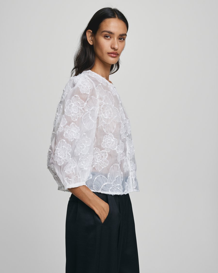 MSCH Copenhagen ISMENE 3/4 Shirt EMB in white, crafted from a lightweight semi-sheer fabric with delicate embroidered floral detailing. Designed with a round neckline and full front button closure, featuring 3/4-length volume sleeves with elastic cuffs and an oversized airy fit.