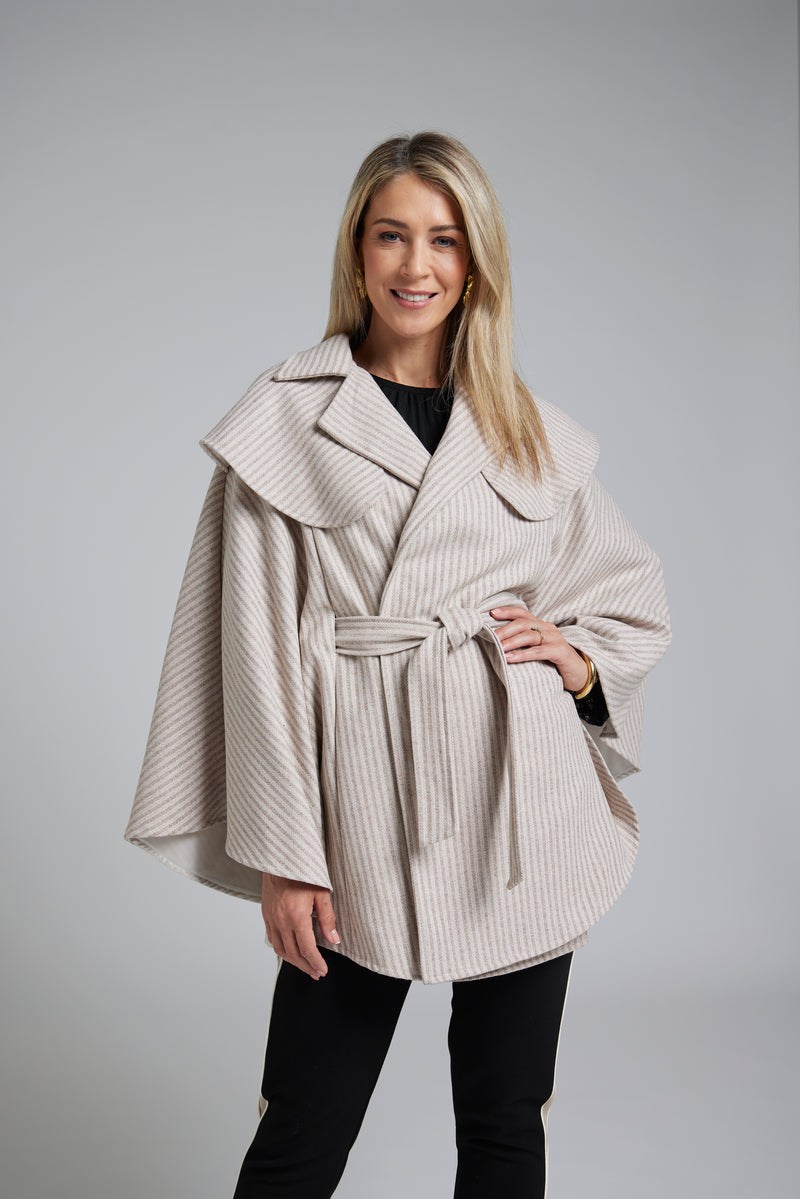 The NES Suri Cape by N-E-S – a trench-inspired wool cape Herringbone with waist tie, lapel and full lining. A refined winter show stopper. NZ made.