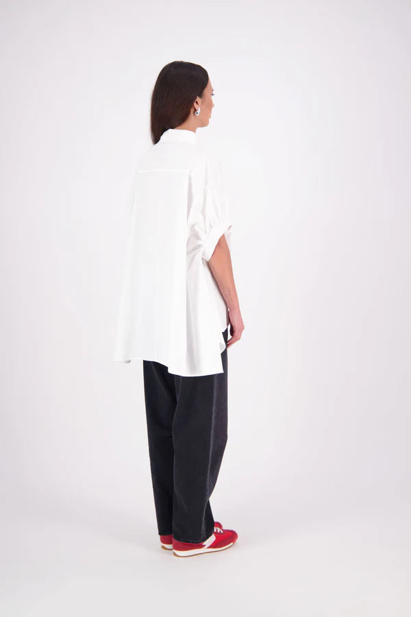 Ryn cotton Shirt – Effortless Volume & Soft Structure

The N-E-S Ryn Shirt is a modern take on a classic, crafted in breathable cotton. With its umbrella-style silhouette, it features a centre front button-down placket, kimono-style sleeves gathered into soft cuffs, and a slight high-low hem. Easy to style back with pants, shorts, or skirts—this is your go-to shirt for relaxed yet elevated dressing.